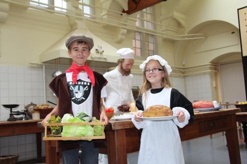 Children dressed as servants in the Hall for the Hands on History Event, standing in the Hall Kitchen